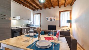 Una cucina moderna con zona pranzo, travi a vista in legno e vista sul soggiorno.