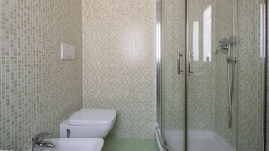 Un baño con inodoro, ducha y paredes de azulejos.