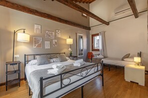A bedroom with a large bed, a smaller bed, a desk, and a chair. There are wall-mounted lamps, a window with curtains, and artwork on the walls. - Herion Palace Apt. 5 by Wonderful Italy (Venecia)