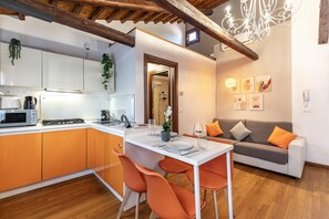 A modern kitchen with a dining area, wooden beams, and a grey sofa with orange cushions. - Herion Palace Apt. 5 by Wonderful Italy (Venecia)