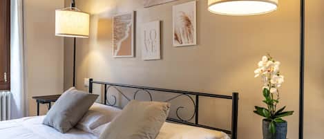 A neatly made bed with pillows, a bedside table with a lamp, and wall art.