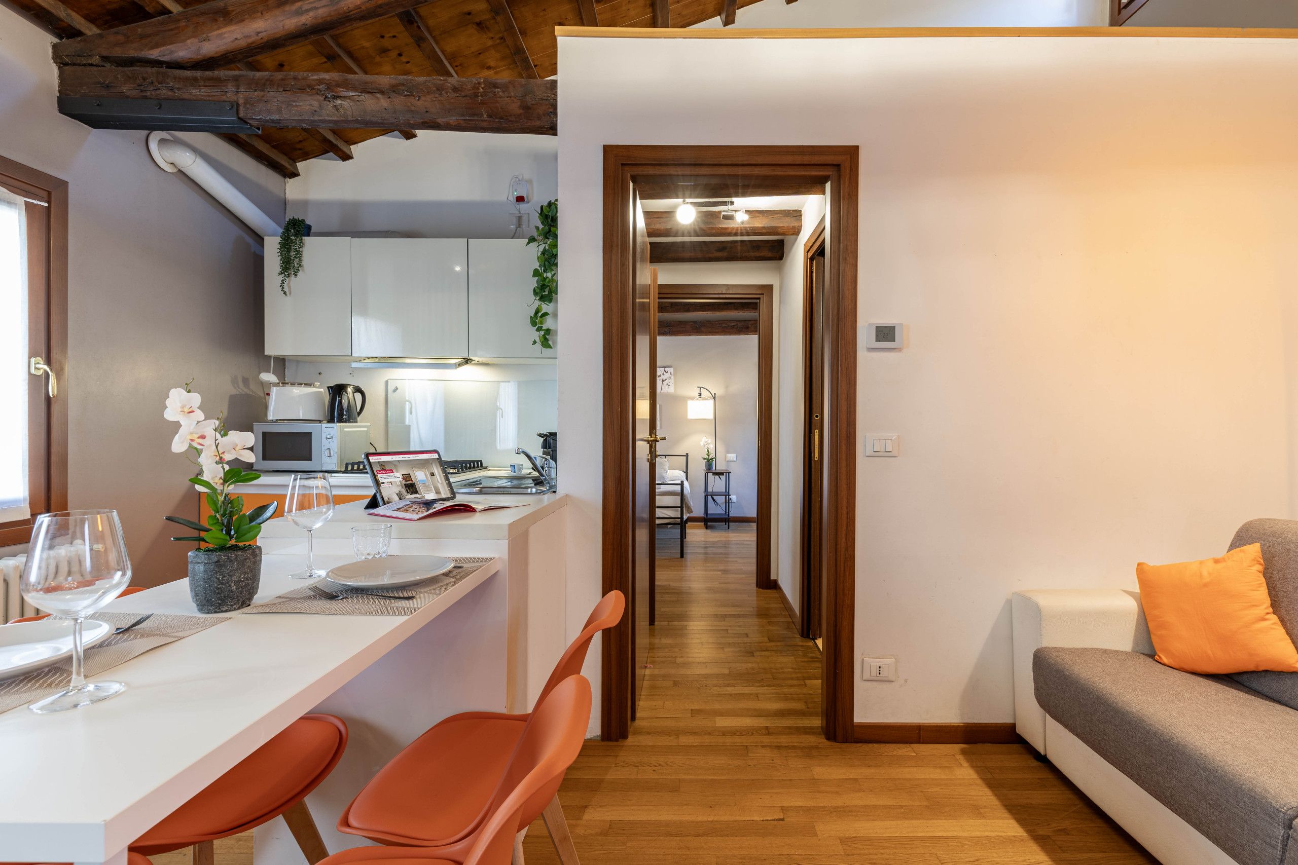 A modern kitchen with white cabinets, a dining area with a white table, and a wooden floor.