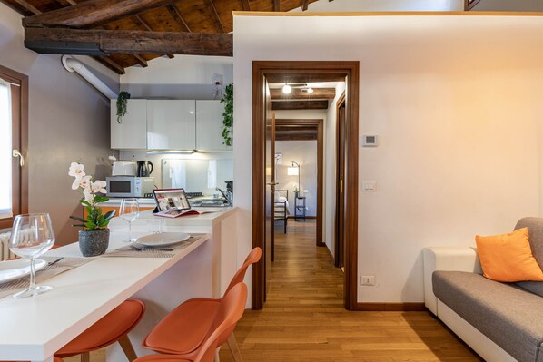 A modern kitchen with white cabinets, a dining area with a white table, and a wooden floor. - Herion Palace Apt. 5 by Wonderful Italy (Venecia)
