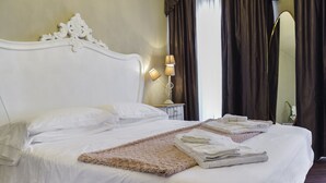 Un lit bien fait, avec du linge de lit blanc, un plaid beige moelleux et des serviettes pliées.