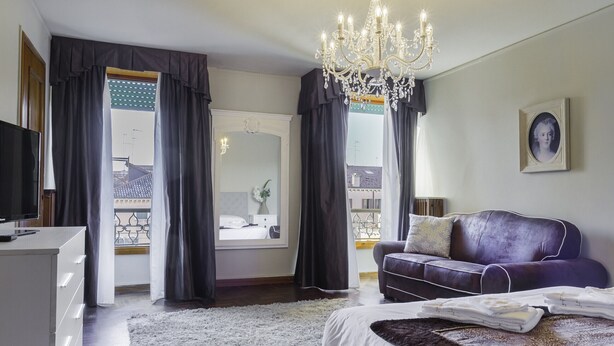 Une chambre moderne avec un grand lit, une commode, un téléviseur et un lustre.
