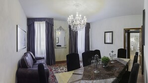 Une salle à manger avec un lustre, une table à manger dressée pour six personnes et un canapé.
