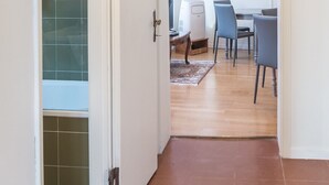 Eine offene Tür, die in ein Badezimmer mit Duschkabine und einen Essbereich mit Tisch und Stühlen führt.