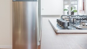 Eine Küche mit einem Edelstahl-Kühlschrank, einem weißen Schrank und einem Gasherd.