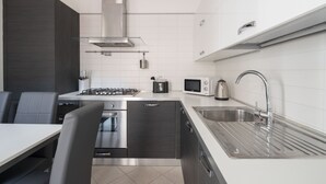 A modern kitchen with a gas stove, microwave, sink, and stainless steel appliances. - San Marco Penthouse 2 by Wonderful Italy (Venecia)