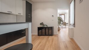A modern kitchen with dark cabinets, a wooden countertop, and a dining area with a table and chairs. - San Marco Square With Terrace by Wonderful Italy (Venecia)