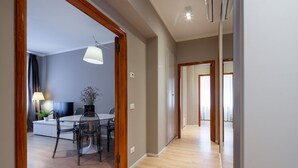 Un intérieur moderne comprenant un coin repas, un téléviseur et un couloir menant à une autre pièce.