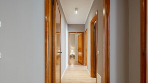 A hallway with wooden doors and a light-colored floor, leading to a room with a lamp. - San Marco Suite 2 by Wonderful Italy (Venecia)
