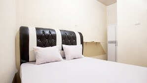 Un dormitorio con una cama grande, cabecera blanco y negro y un armario blanco.