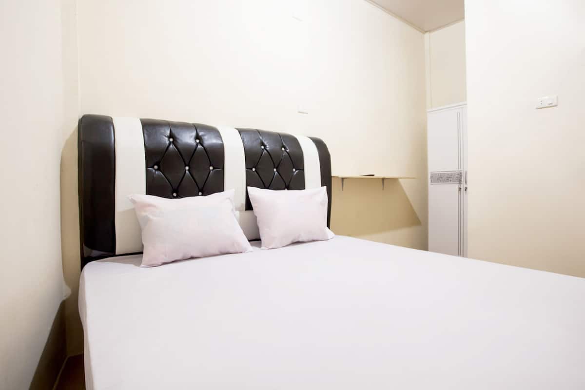 A bedroom with a large bed, a black and white headboard, and a white wardrobe.