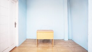 Un pequeño escritorio de madera en una habitación con paredes azul claro y suelo de madera.