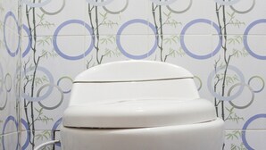 Un inodoro en un baño con pared estampada y suelo de azulejos azules.