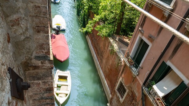 A narrow canal with boats, a building with a balcony, and a rope barrier. - Venice Grand Canal Style Apt. 2 by Wonderful Italy (Venecia)