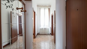 A hallway with a tiled floor, wooden doors, and a window with sheer curtains. - Venice Grand Canal Style Apt. 2 by Wonderful Italy (Venecia)