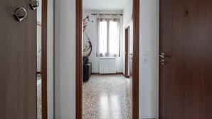 Ein Flur mit Holztür, Heizkörper und einem Fenster mit Vorhängen.
