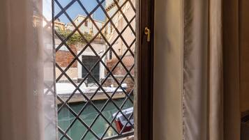 Una finestra con una griglia metallica, una porta con maniglia dorata e vista su un edificio con il cartello 'DENTI SALVIA'.