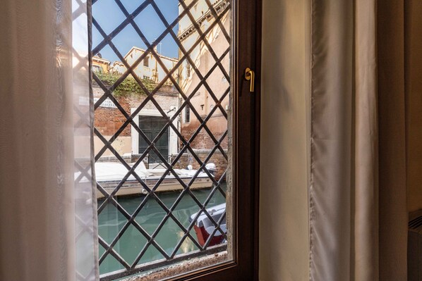 A window with a metal grid, a door with a golden handle, and a view of a building with a sign that reads 'DENTI SALVIA'.