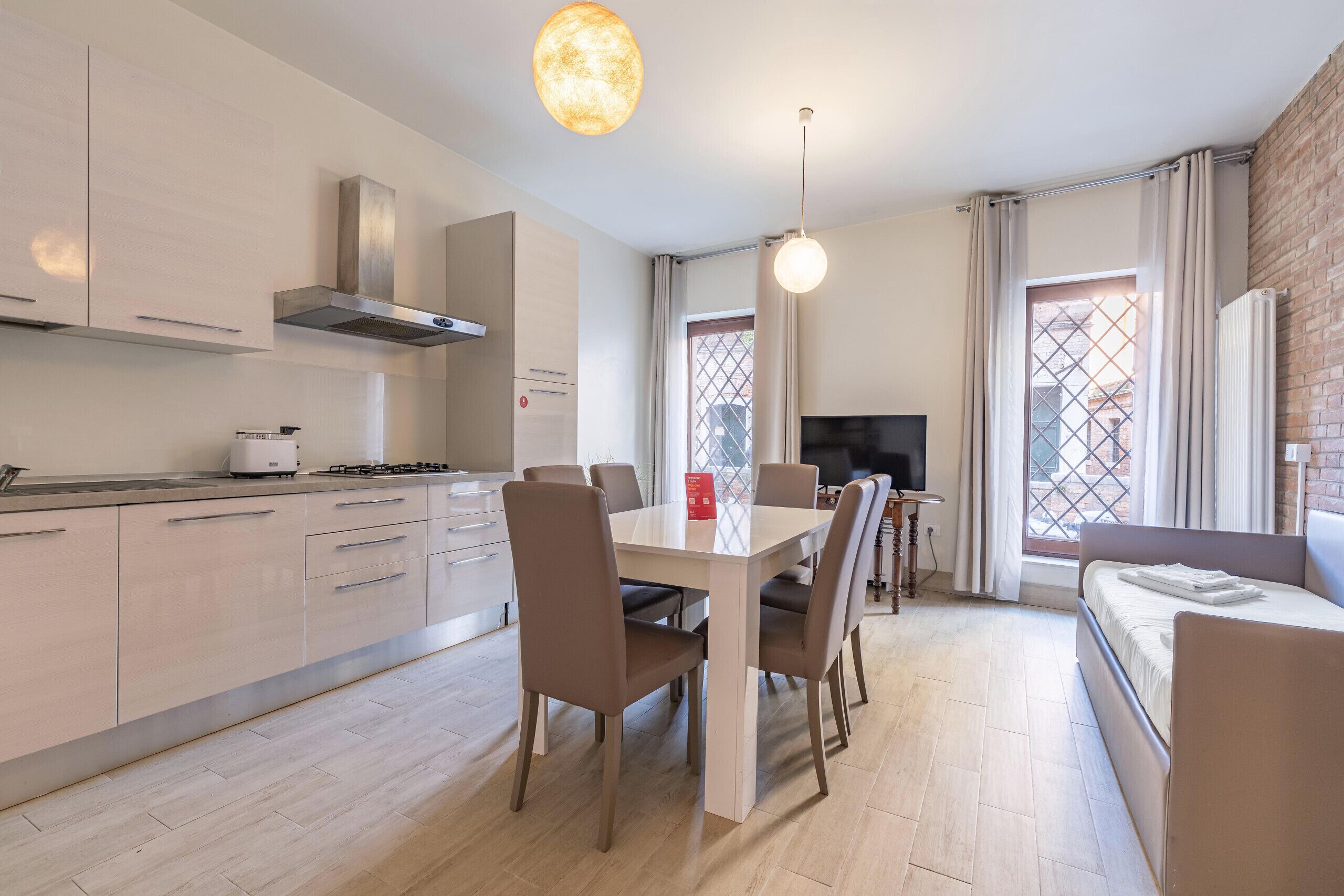 A modern kitchen with a dining area, a TV, and a sofa.