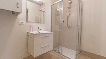 Une salle de bain moderne avec une douche à parois de verre, un meuble-lavabo blanc doté de tiroirs et un miroir au-dessus du lavabo.