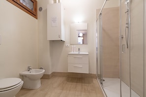 A bathroom with a toilet, bidet, sink, mirror, and a glass-enclosed shower. - Venice Luxury Palace 1 by Wonderful Italy (Venecia)
