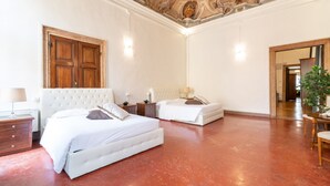 Ein geräumiges Schlafzimmer mit zwei Betten, einer Holztür und einem rot gefliesten Boden.