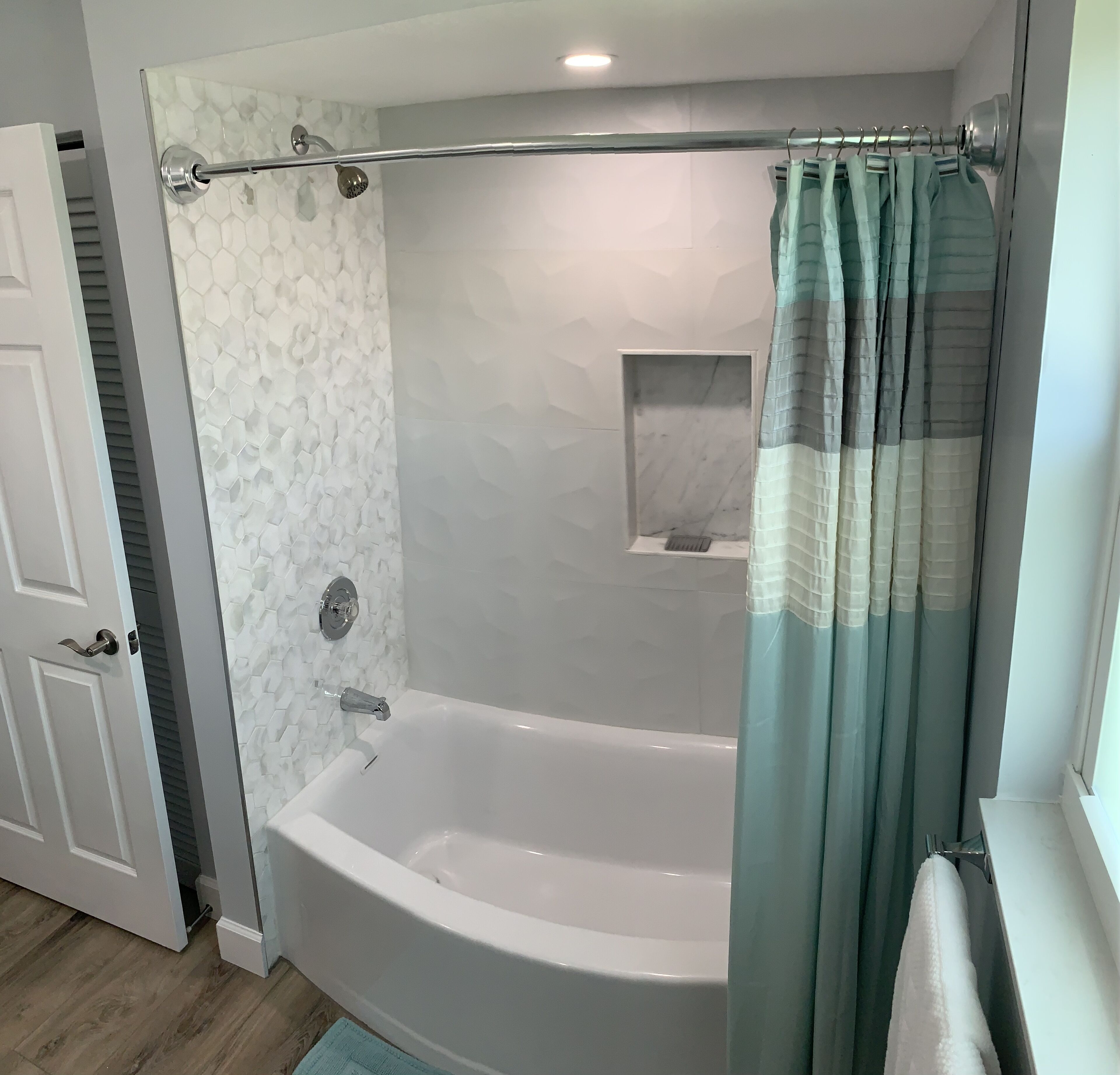 Ein Badezimmer mit Badewanne, Duschvorhang und kleinem Fenster.