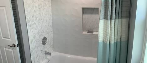 Ein Badezimmer mit Badewanne, Duschvorhang und kleinem Fenster.