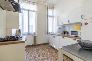 A modern kitchen with white cabinets, a gas stove, a microwave, and a sink.