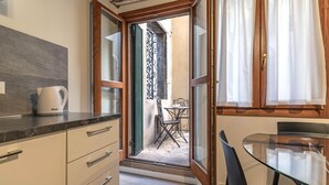 Una cocina compacta con cafetera, una mesa de vidrio y vistas del patio exterior.