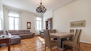 A living room with a sofa, a dining table with chairs, a chandelier, and a bookshelf. - Venice Luxury Palace 6 by Wonderful Italy (Venecia)