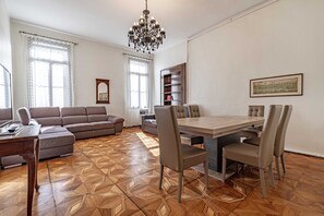 A living room with a sofa, a dining table with chairs, a chandelier, and a bookshelf. - Venice Luxury Palace 6 by Wonderful Italy (Venecia)