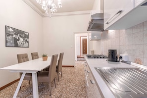 A modern kitchen with a gas stove, a coffee maker, and a chandelier.