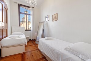 A hotel room with two beds, a large mirror, and a window with a view of buildings.