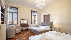 A hotel room with a large bed, a desk, a chair, and a chandelier. - Venice Luxury Palace 6 by Wonderful Italy (Venecia)