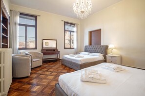 A hotel room with a large bed, a desk, a chair, and a chandelier. - Venice Luxury Palace 6 by Wonderful Italy (Venecia)