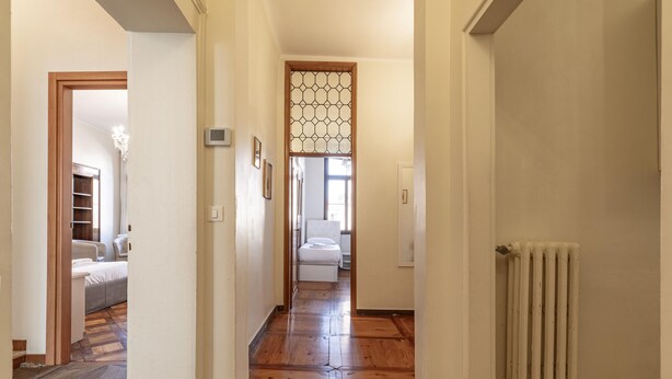 A hallway with wooden flooring, a radiator, and a bed in the background. - Venice Luxury Palace 6 by Wonderful Italy (Venecia)