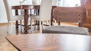 Un comedor con una mesa de madera, cuatro sillas, un florero con flores y dos cuadros en la pared.