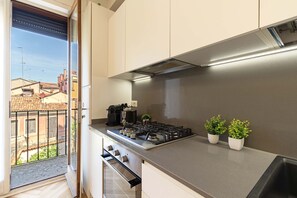 Une cuisine moderne équipée d’une cuisinière à gaz, d’une machine à café et de deux plantes en pot posées sur le plan de travail.
