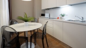 Une cuisine moderne avec des meubles blancs, un four à micro-ondes, un évier et un coin repas comprenant une table et des chaises.