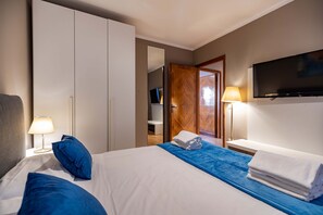Una habitación de hotel con cama, armario, televisor y baño.