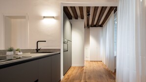 A modern kitchen with a central island, wooden flooring, and a view of the adjacent living area.