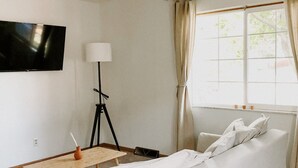 Un salon moderne avec un canapé, une petite table, une lampe et un téléviseur fixé au mur.