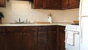 Une cuisine avec des meubles en bois, un fourneau blanc et un dosseret carrelé.