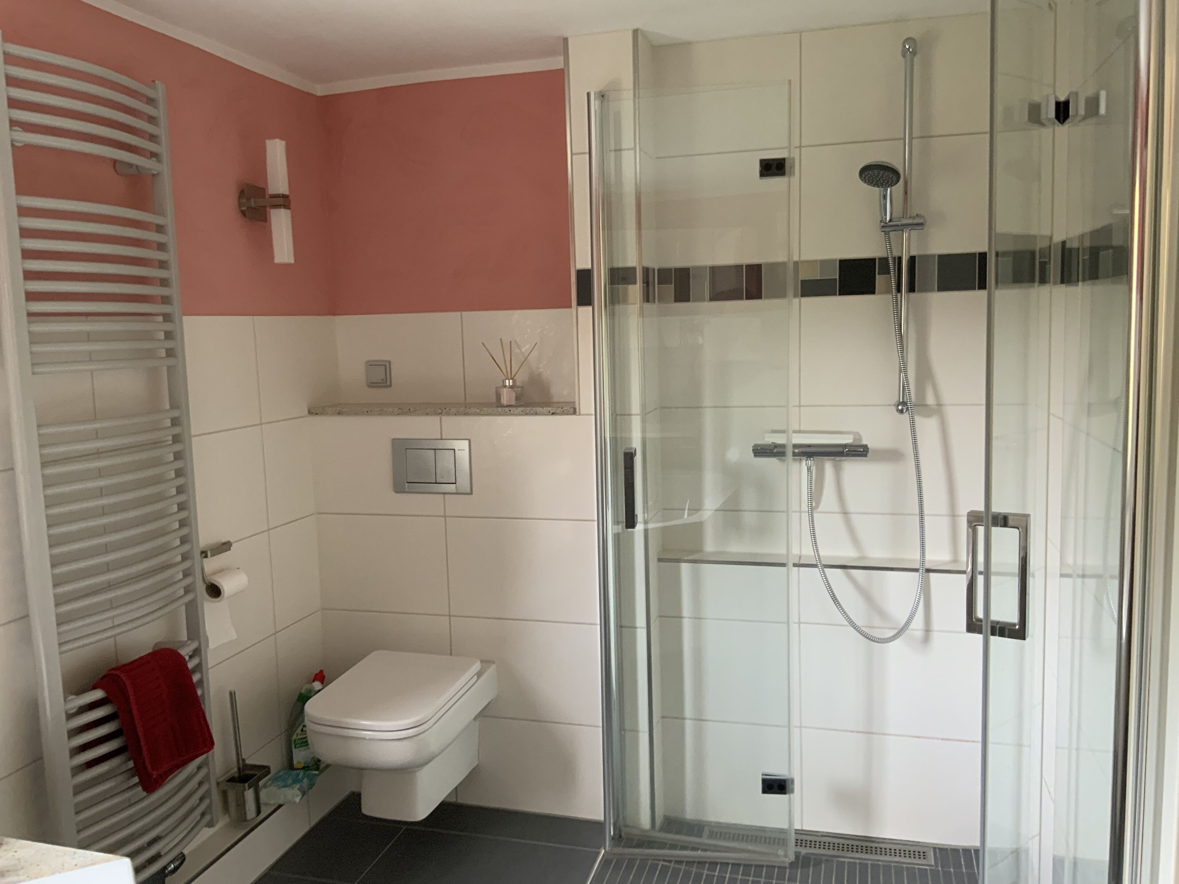 Un baño moderno con ducha de vidrio, inodoro y perchero para toallas.