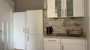 A compact kitchen with white cabinets, a stainless steel sink, and a coffee maker.