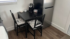 Ett litet, praktiskt kök med kylskåp, kaffebryggare och ett litet bord med stolar.